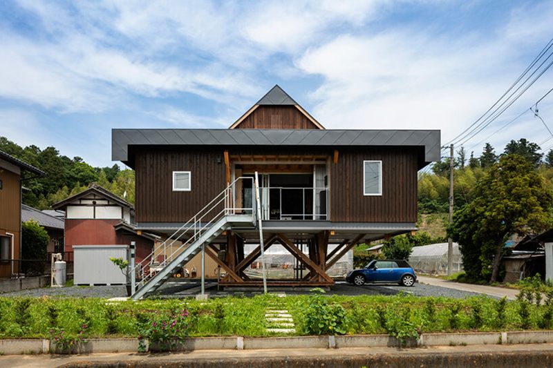Rumah panggung kotak sederhana dengan dinding kayu vertikal dan atap datar ala Jepang